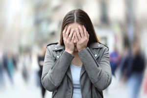 young woman in a public park with her head in her hands struggling with common phobias and how to manage them