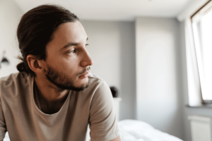 young man seated on his bed contemplating effective mindfulness techniques for depression