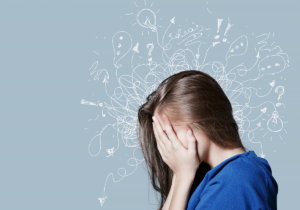 A woman is holding her head in her hands as she experiences chronic anxiety.