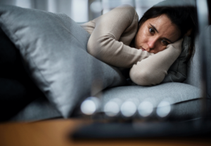 young woman looking distraught as she lies awake in bed struggling with understanding atypical depression