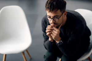 A man is sitting in a chair and wondering if he is experiencing compulsive vs. impulsive behaviors.