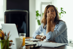 A woman is sitting at her computer and biting her nails. She's wondering whether she's experiencing anxiety or autism.