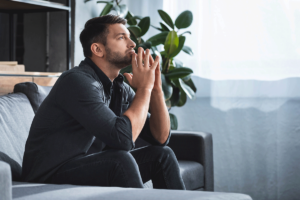 A man is sitting on a couch and thinking about his trauma and memory loss.