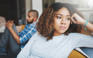 A man and a woman sit on a couch, facing away from one another. Their relationship is being effected by ADHD.