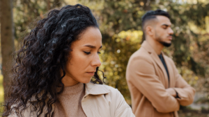 A man and a woman stand facing away from one another. They are in a toxic relationship.