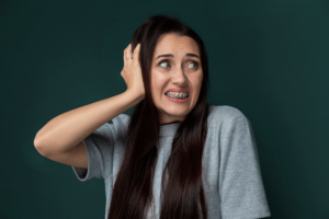 A woman with ADHD has her hand pressed to her ear and is grimacing. She is engaging in stimming behavior.